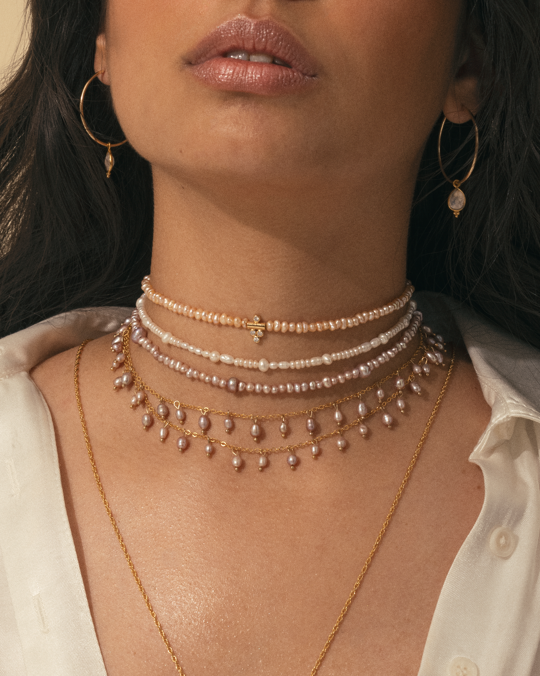Femme portant une accumulation de colliers nacrés APSARA : le collier DALHIA (perles roses) et le collier Pearl.
